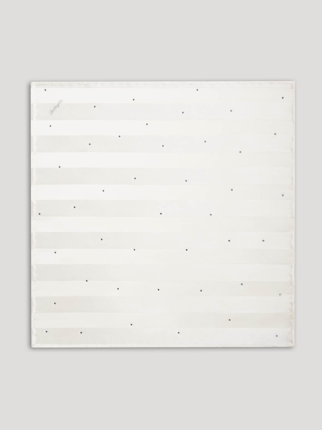 White silk handkerchief with green swarovski details close up.