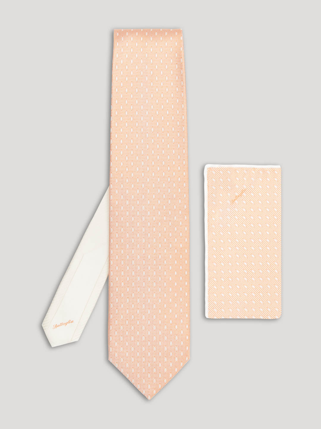 Peach tie with white diamond details on it and matching handkerchief.