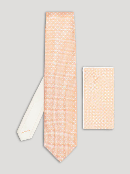 Peach tie with white diamond details on it and matching handkerchief.