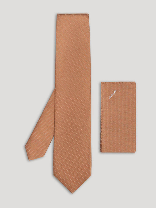 Brown tie with small white polkadots and matching handkerchief.