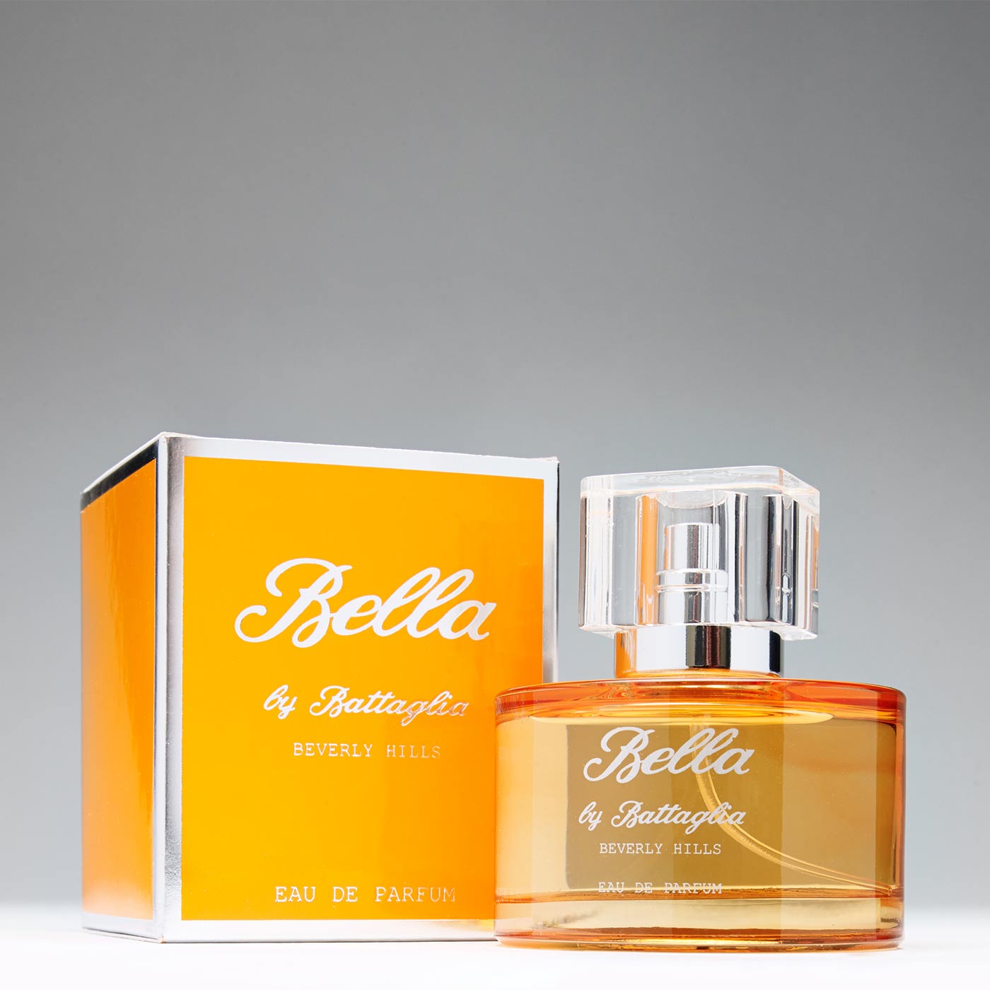 Bella by Battaglia. Sweet and ambrosial, Bella is a vivacious fragrance for women who are attracted to a playful scent. Photo shows Bella fragrance in an orange bottle next to its orange box.