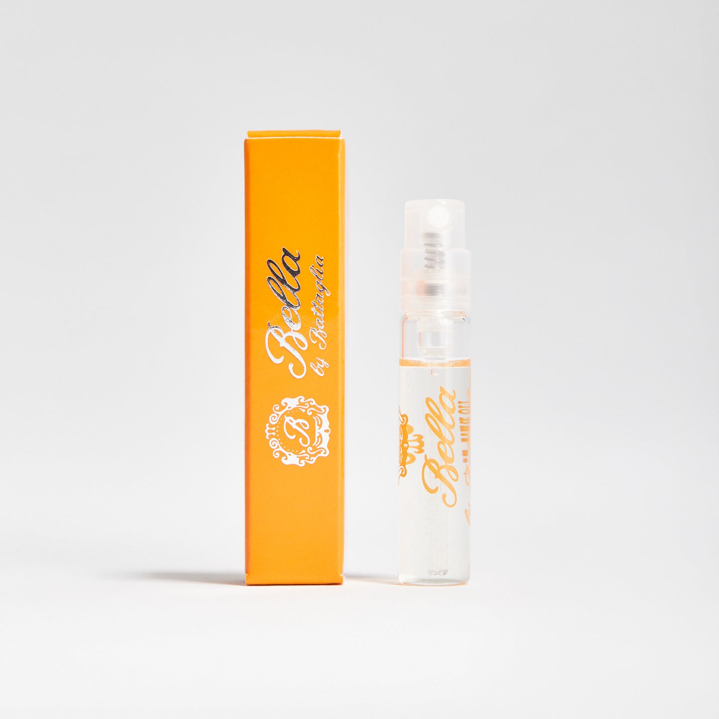 A photo of the Bella fragrance sample by Battaglia. The sample is standing upright next to the orange box it is packaged in against a white background.