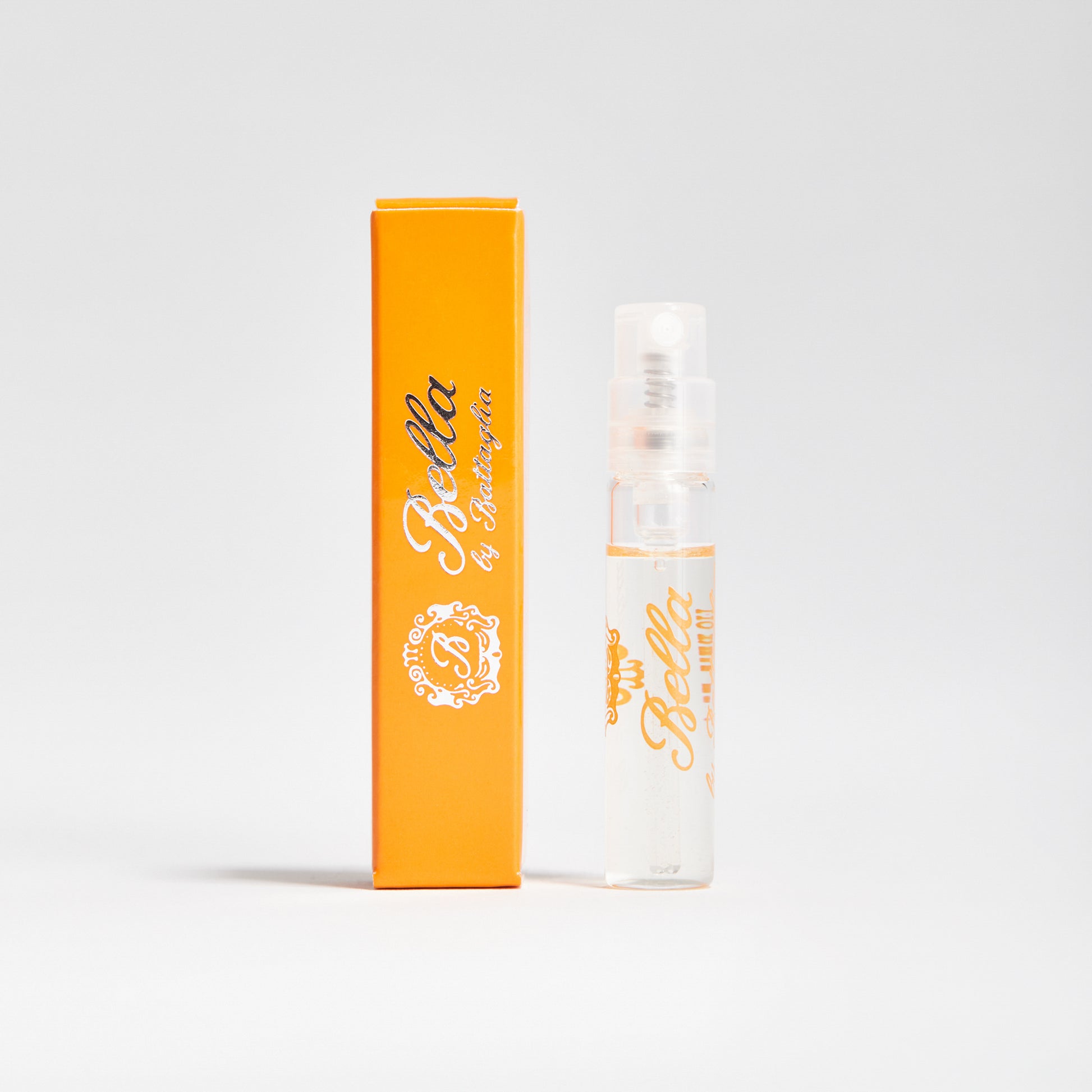 A photo of the Bella fragrance sample by Battaglia. The sample is standing upright next to the orange box it is packaged in against a white background.