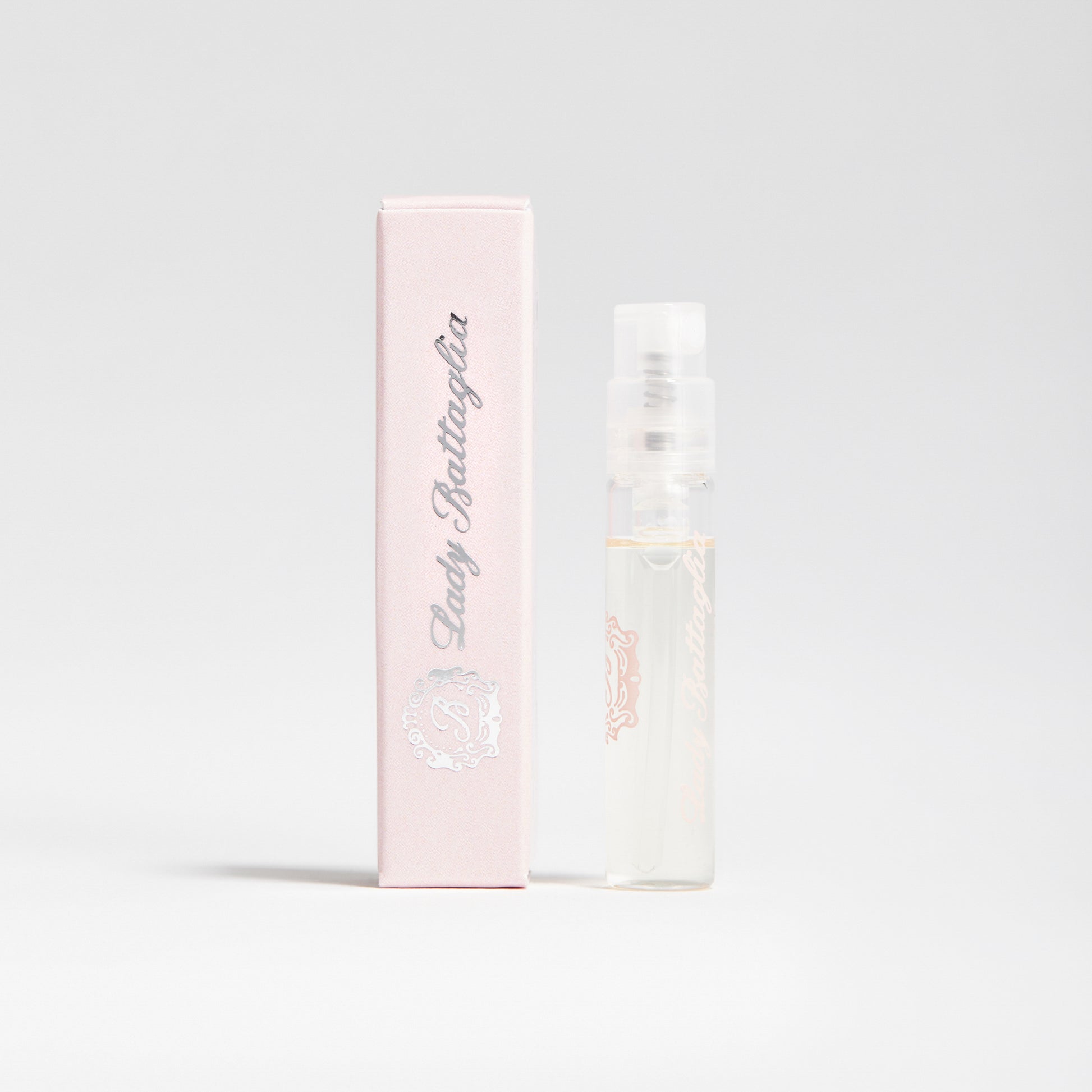 A photo of the Lady Battaglia fragrance sample by Battaglia. The sample is standing upright next to the pink box it is packaged in against a white background.