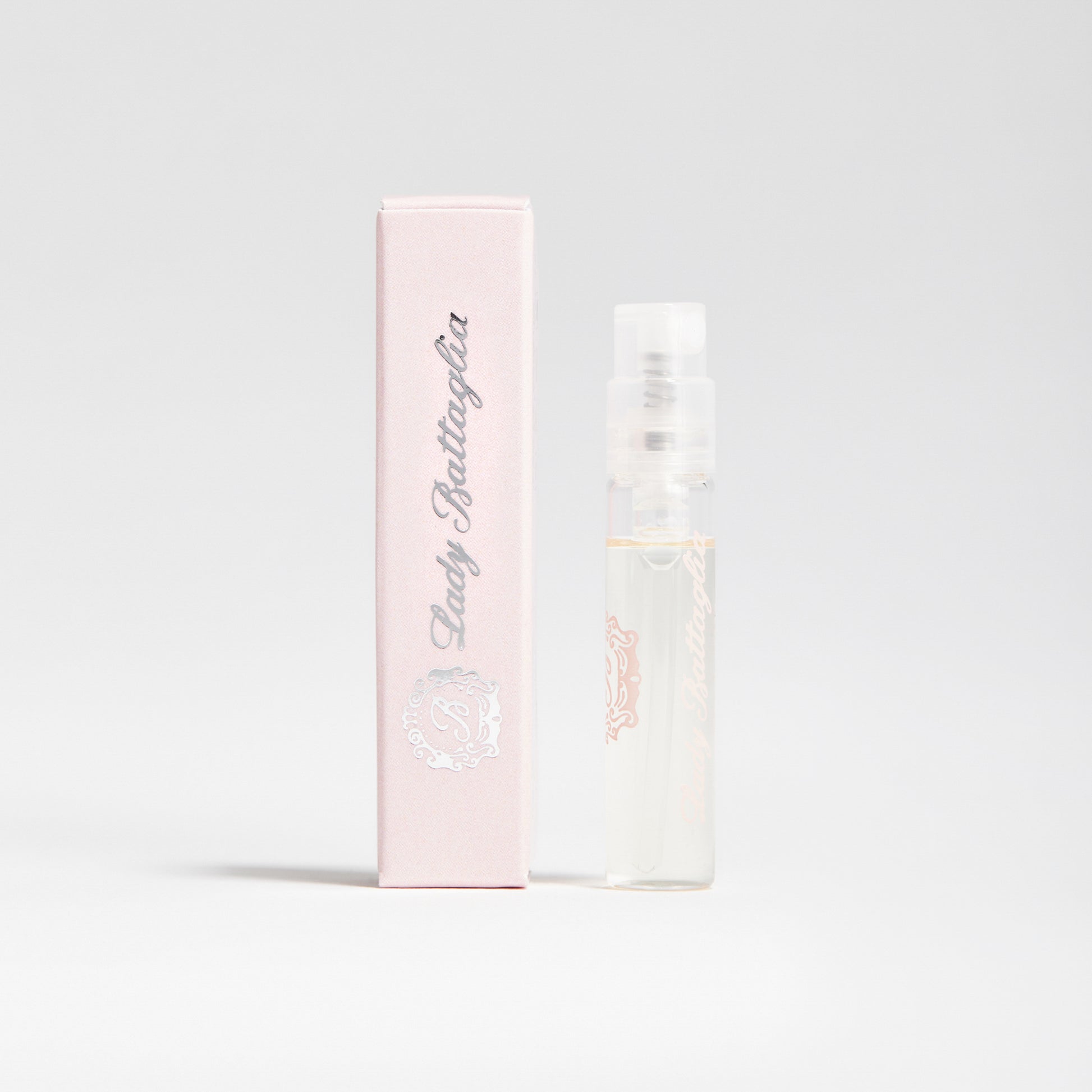 A photo of the Lady Battaglia fragrance sample by Battaglia. The sample is standing upright next to the pink box it is packaged in against a white background. 