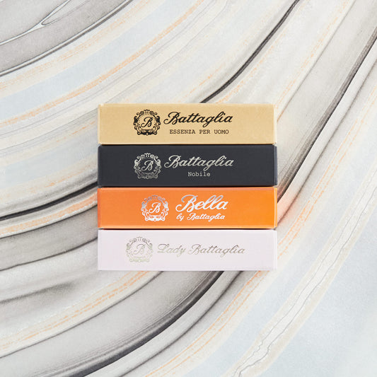 Four Battaglia fragrance sample boxes placed on a grey marbled background